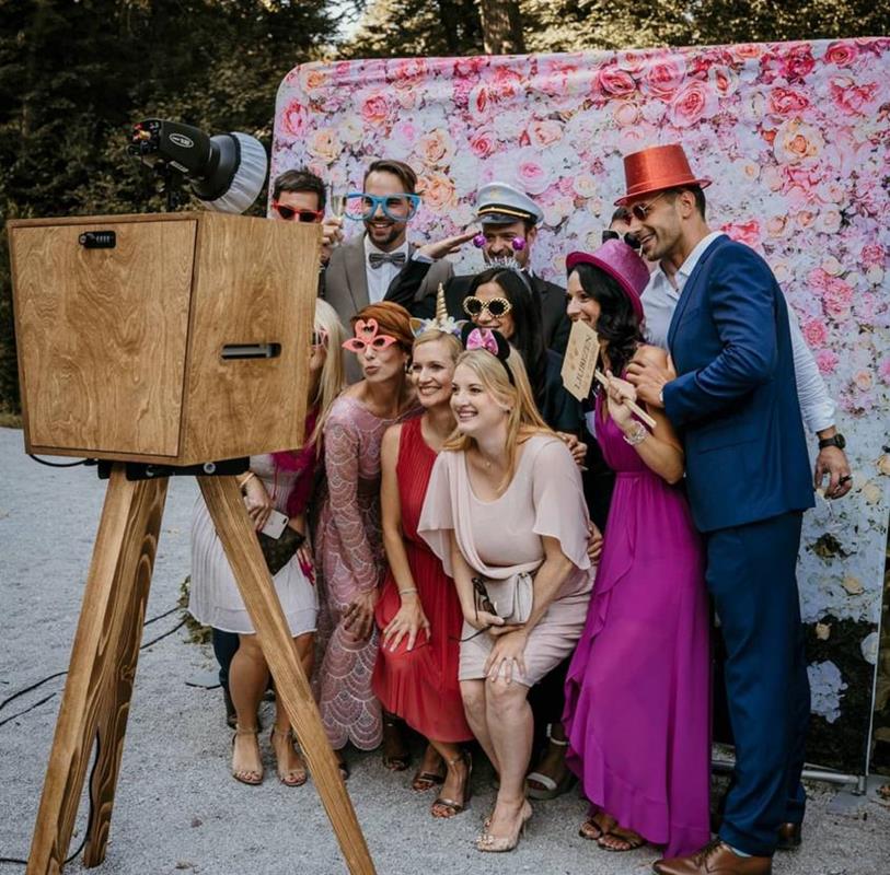 Large group posing at an open air photo booth with floral backdrop